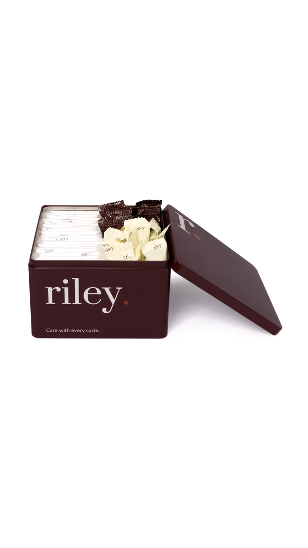 A dark brown metal tin with its lid propped open, showing pads and tampons inside, on a clean white background.